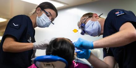 two masked Air Force Dental specialists performing surgery on an Aviator.