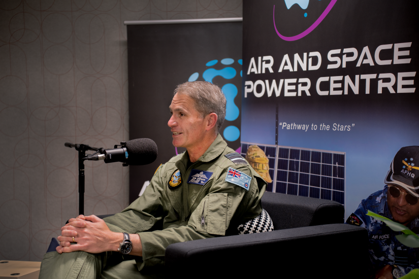 Chief of Air Force Rob Chipman sitting in navy blue coloured arm chairs with air and space power centre pull up banners behind him. In front of him is a microphone on a stand 