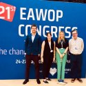 Four people standing in front of a blue media wall with white text saying 21st EAWOP Congress