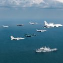 A Royal Australian Air Force E-7A Wedgetail leads a formation of aircraft past the Italian Navy aircraft carrier ITS Cavour during Exercise Pitch Black 2024.