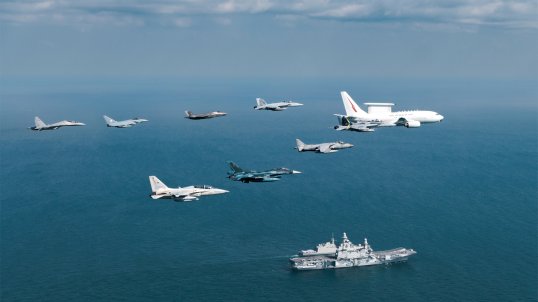 A Royal Australian Air Force E-7A Wedgetail leads a formation of aircraft past the Italian Navy aircraft carrier ITS Cavour during Exercise Pitch Black 2024.