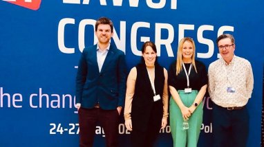 Four people standing in front of a blue media wall with white text saying 21st EAWOP Congress